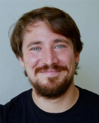Headshot of Paulus Wagner in front of a blue-green background