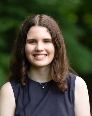 Headshot of Sydney Black in front of a background with trees