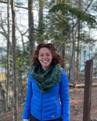 Headshot of Mariam Gleckman-Krut situated against a background of trees. 