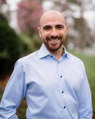 Lewis Krashinsky headshot in front of blurred outdoor scenery. 