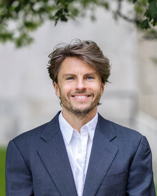 Rouven Symank headshot in front of greenery