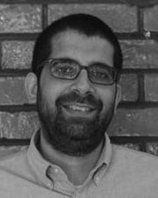 Headshot of Puneet Bhasin in front of a brick wall