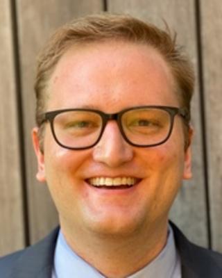 Headshot of Derek Robey in front of a wooden background