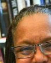Headshot of Evelynn Hammonds sitting in front of book shelves and smiling