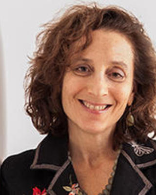 Peggy Levitt_leaning on a white wall smiling