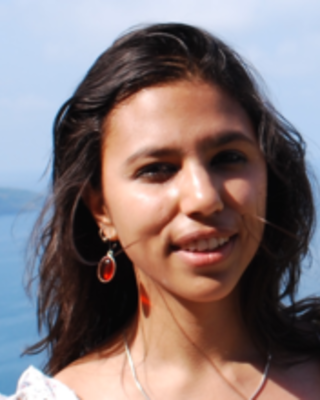 Headshot of Poulomi Chakrabarti standing outside by water