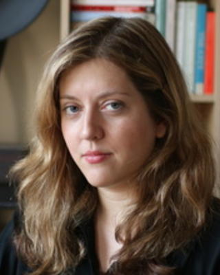 Headshot of Anna Skarpelis in front of a bookshelf