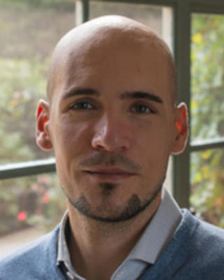 Headshot of Stefan Beljean standing by a window