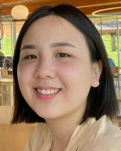 Headshot of Meera Choi in front of tables in a gathering space