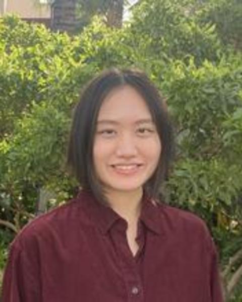 Headshot of Jingyun Dai in front of bushes and other greenery