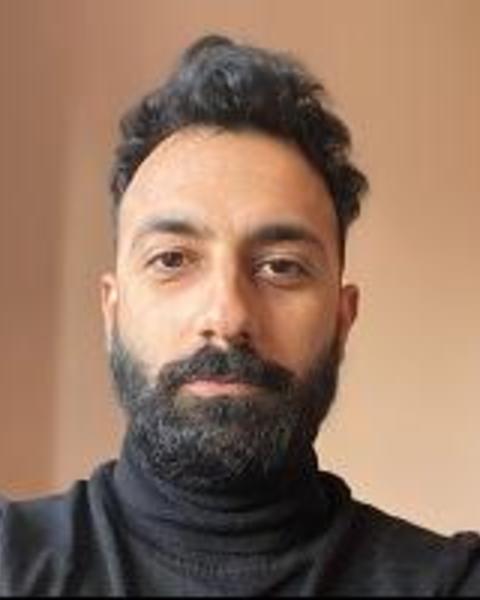Headshot of Ali Meghji in front of a beige background