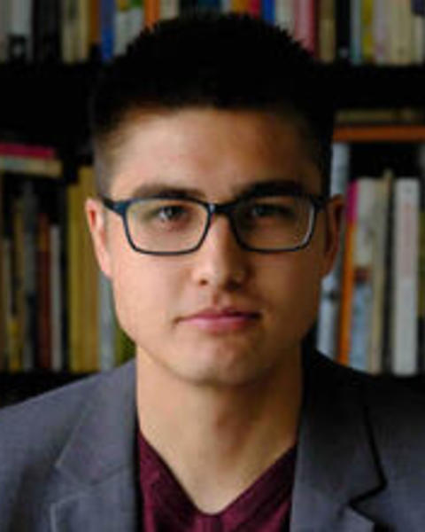 Headshot of Galen Watts in front of books