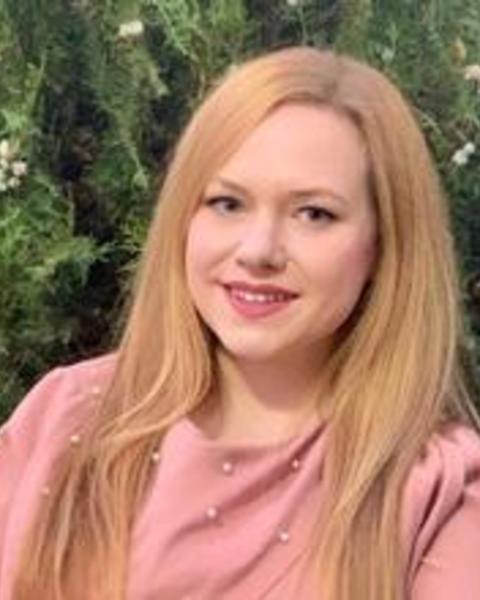 Headshot of Merih Angin standing in front of a tree