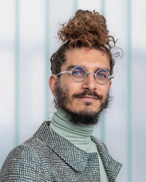 Headshot of Luca Carbone set against a blurred and striped background 