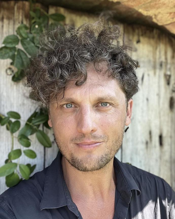 Headshot of Dominik Bartmanski in front of a background with a vine. 