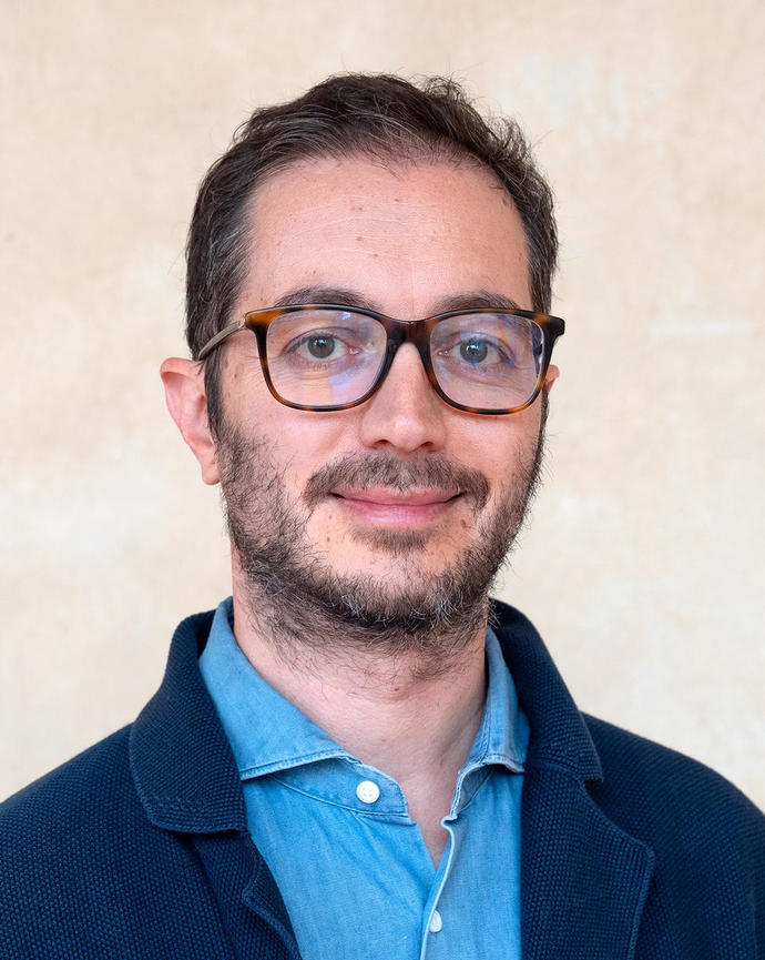 Headshot of Gianluca Busilacchi in front of a beige background