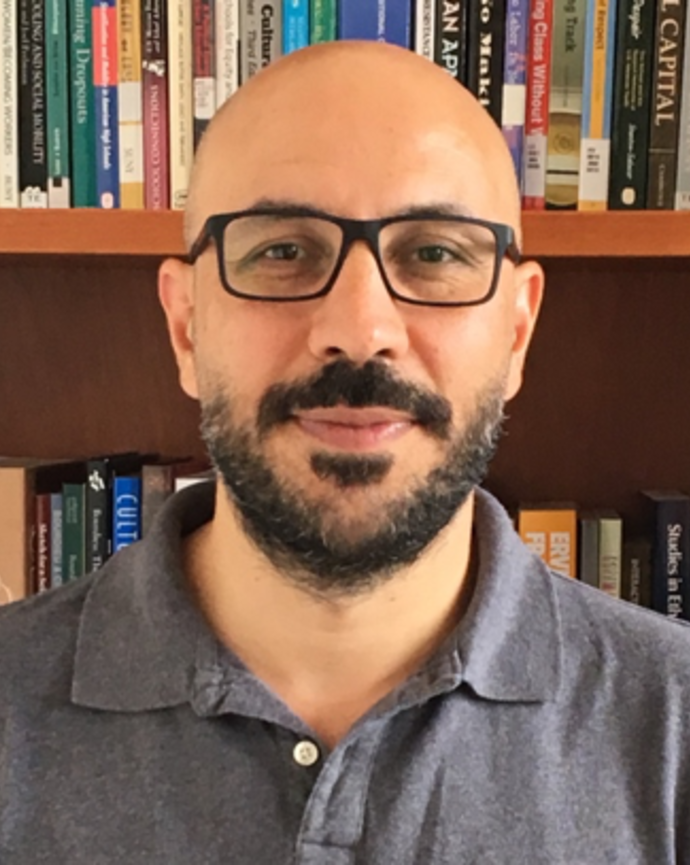 Headshot of Cetin Celik standing in front of a bookshelf