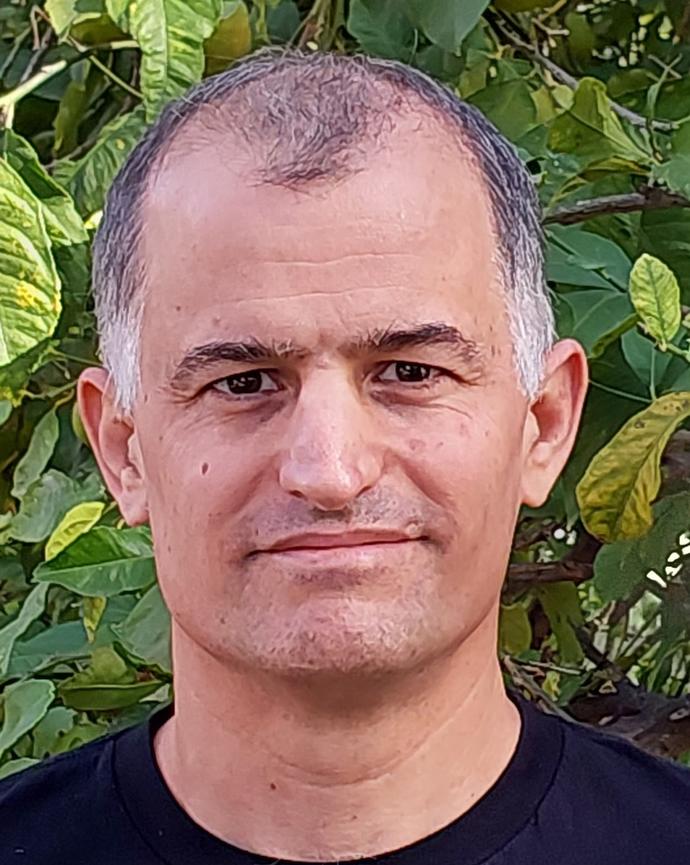 Headshot of Yuval Feinstein in front of greenery