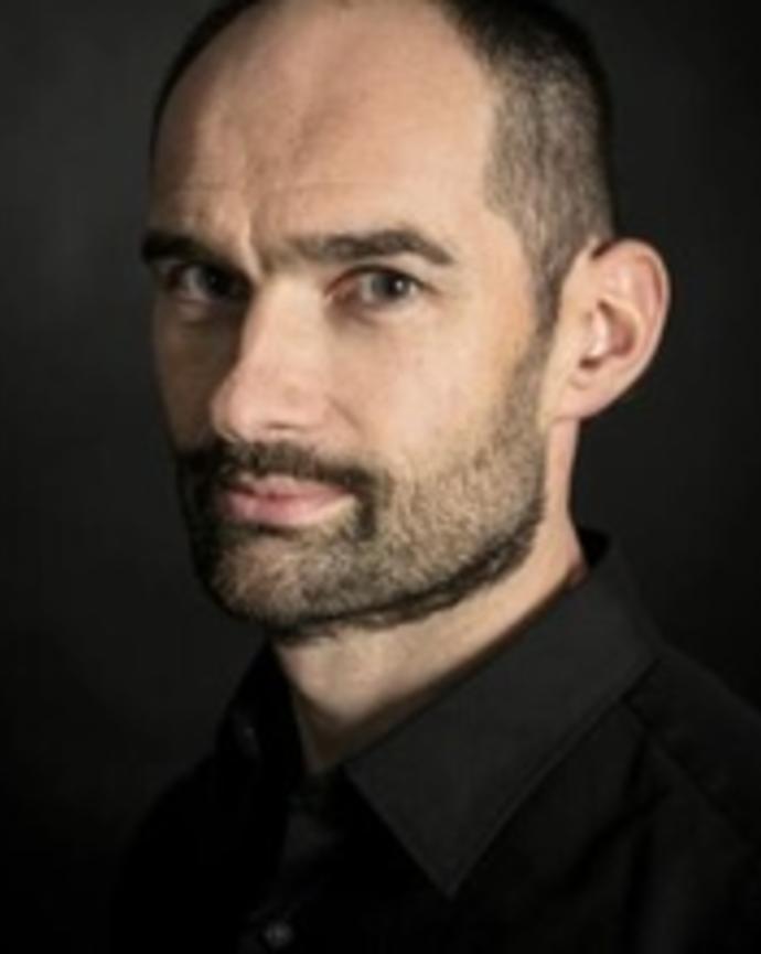 Headshot of Arnaud Esquerre in front of a dark background