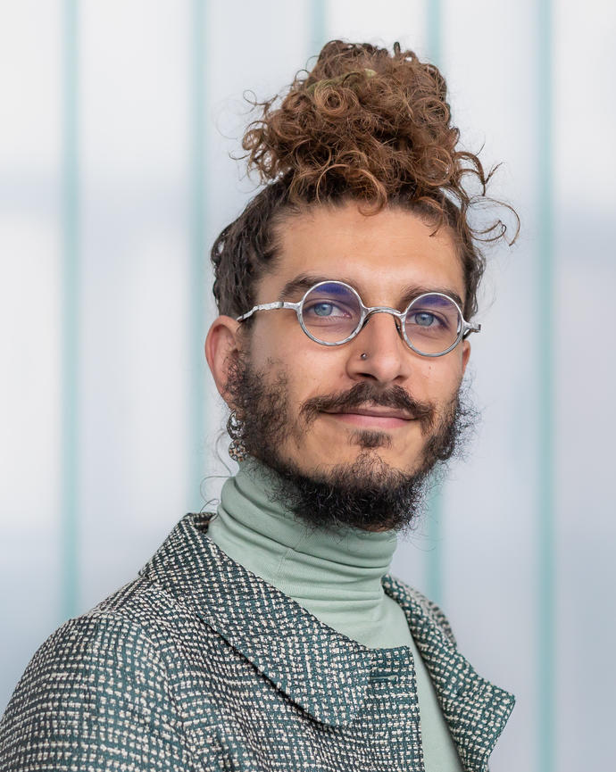 Headshot of Luca Carbone set against a blurred and striped background 