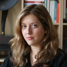 Headshot of Anna Skarpelis in front of a bookshelf
